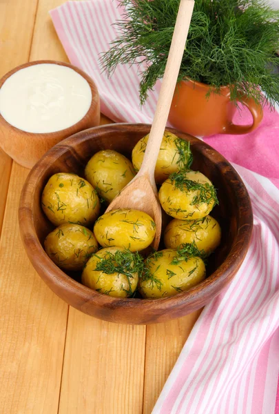 Boiled potatoes on wooden bowl near napkin on wooden table — Stock Photo, Image
