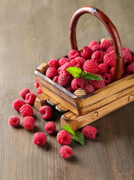 Reife süße Himbeeren im Korb auf Holzgrund — Stockfoto