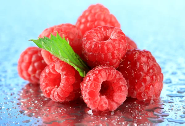 Reife süße Himbeeren mit Tropfen, auf blauem Hintergrund — Stockfoto