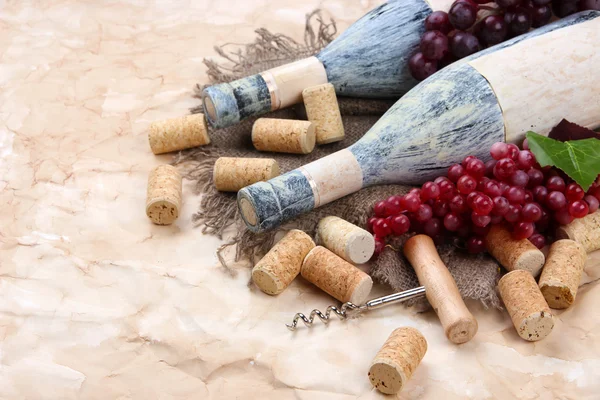 Old bottles of wine, grapes and corks on old paper background — Stock Photo, Image