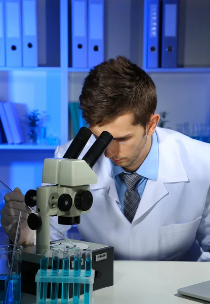 Científico de laboratorio joven mirando el microscopio en el laboratorio — Foto de Stock