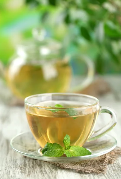 Cup of herbal tea with fresh mint flowers on wooden table — Stock Photo, Image