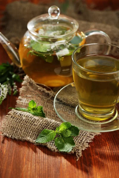 Tasse et théière de tisane aux fleurs de menthe fraîche sur table en bois — Photo