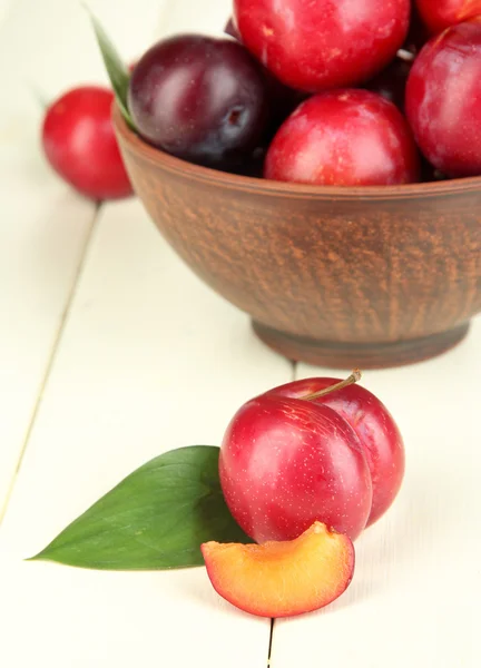 Ripe plums in bowl on wooden table close-up — Stock Photo, Image