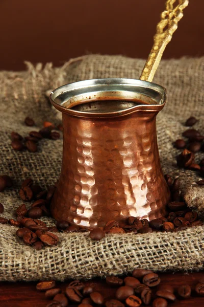 Metalen turk en koffie bonen op bruine achtergrond — Stockfoto