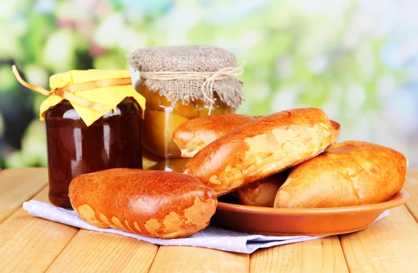 Fresh baked pasties with fruit jam, on wooden table, on bright background — Stock Photo, Image