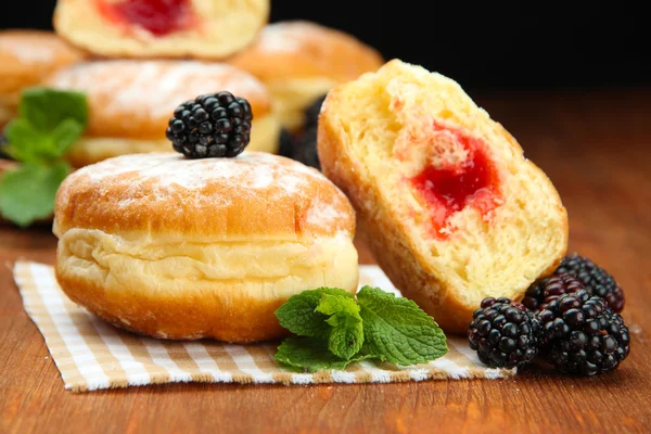 Tasty donuts with berries on wooden table — Stock Photo, Image