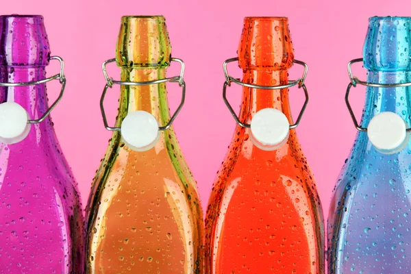 ピンクの背景にカラフルなボトル — ストック写真