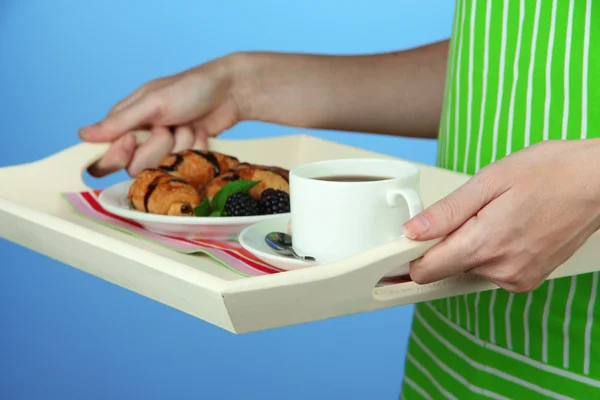 Femme en tablier vert tenant plateau en bois avec petit déjeuner, sur fond de couleur — Photo