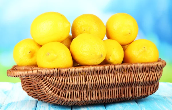 Limones maduros en canasta de mimbre sobre mesa sobre fondo brillante —  Fotos de Stock