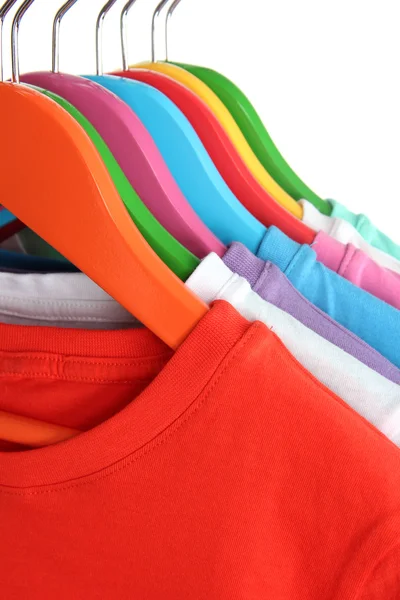 Verschillende shirts op kleurrijke hangers op witte achtergrond — Stockfoto