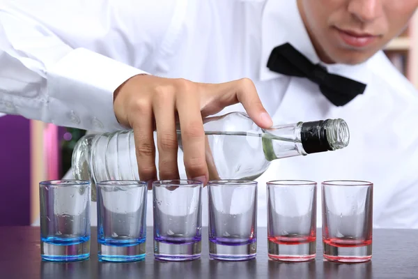 Bartender is pouring vodka into glasses — Stock Photo, Image