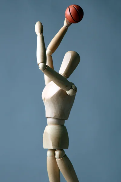 Wooden mannequin with basketball ball on grey background — Stock Photo, Image