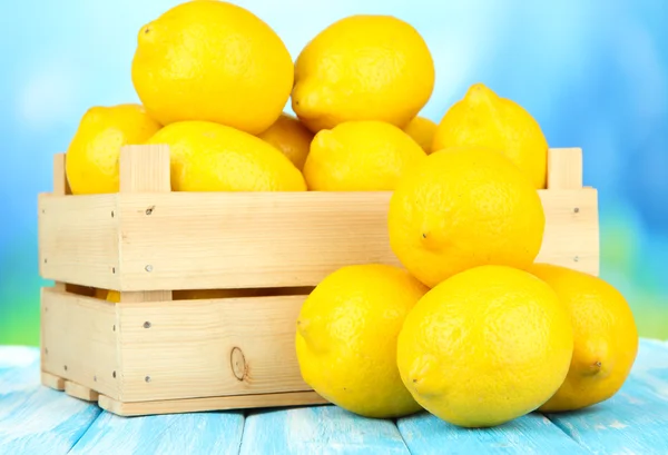 Limoni maturi in scatola di legno sul tavolo su sfondo luminoso — Foto Stock