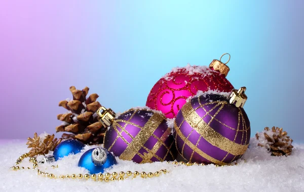 Hermosas bolas de Navidad y conos en la nieve sobre fondo brillante —  Fotos de Stock