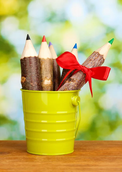 Buntstifte in Eimer auf Holztisch auf hellem Hintergrund — Stockfoto