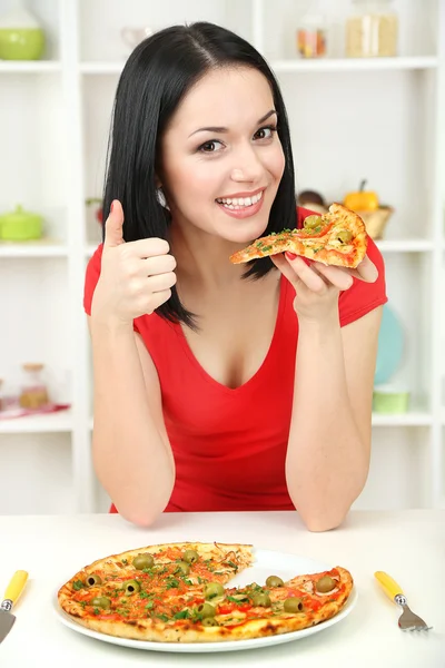 Девушка с вкусной пиццей на фоне кухни — стоковое фото
