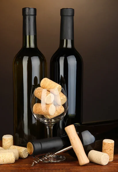 Wine and corks on wooden table on brown background — Stock Photo, Image