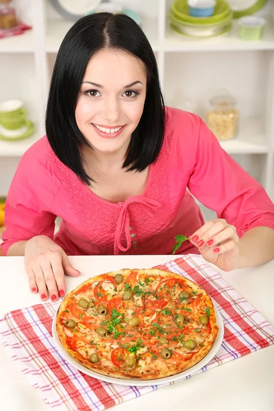 Mooi meisje met heerlijke pizza op keuken achtergrond — Stockfoto