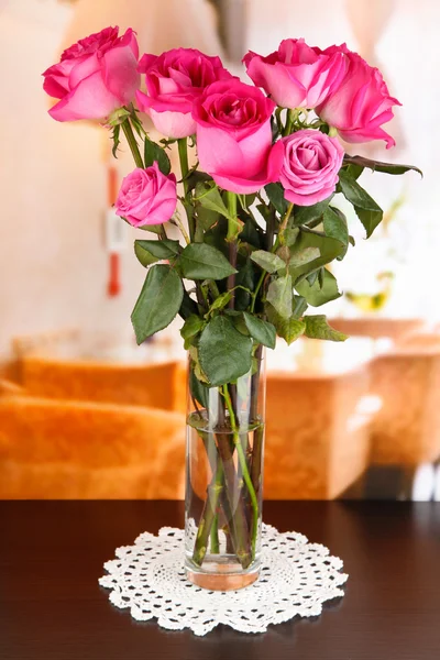 Schöne rosa Rosen in der Vase auf dem Tisch auf dem Hintergrund des Zimmers — Stockfoto