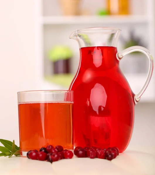 Werper en glas cranberry sap met rode veenbessen op tafel — Stockfoto