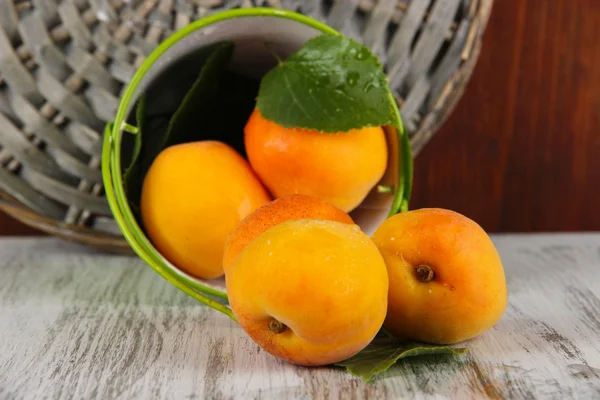 Abricots dans un seau sur une table en bois près des dessous de verre en osier — Photo