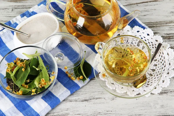 Kettle and cup of tea with linden on wooden table — Stock Photo, Image