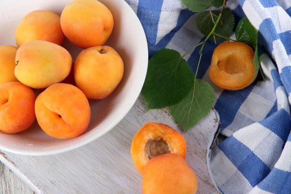 Apricots on board for cutting on napkin on wooden table — Stock Photo, Image