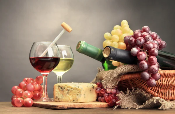 Samenstelling met blauwe kaas, wijn en druivenmost op houten tafel, op grijze achtergrond — Stockfoto
