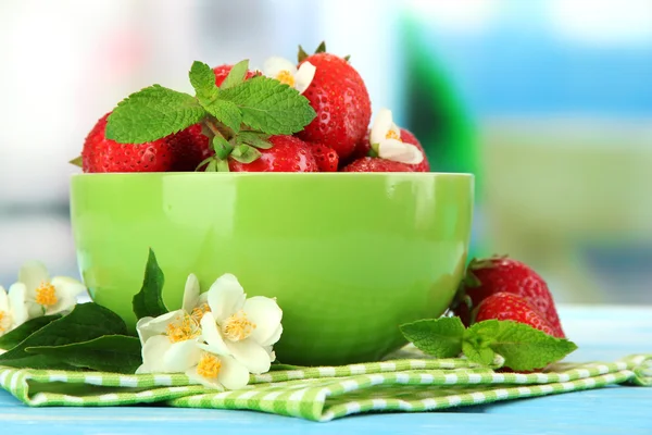 Ripe sweet strawberries in green bowl on blue wooden table — Stock Photo, Image