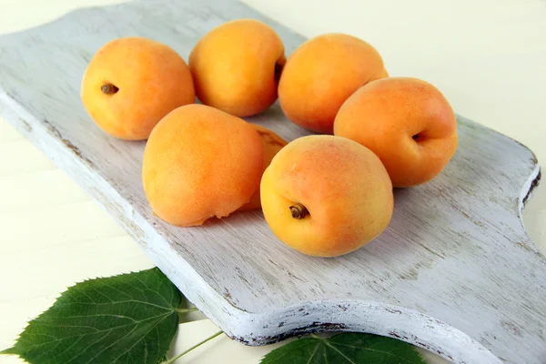 Apricots on board on wooden table — Stock Photo, Image