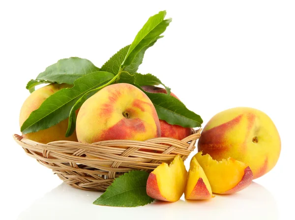 Kypsät makeat persikat lehtineen korissa, eristetty valkoisella — kuvapankkivalokuva