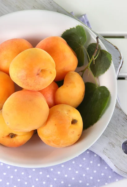 Abricots dans une assiette à bord sur serviette sur table en bois — Photo