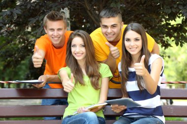 mutlu grup parkta oturan genç öğrenci