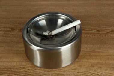 metal kül tablası ve ahşap masa üzerinde Sigara