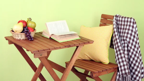 Wooden table with fruit and book on it on green background — Stock Photo, Image