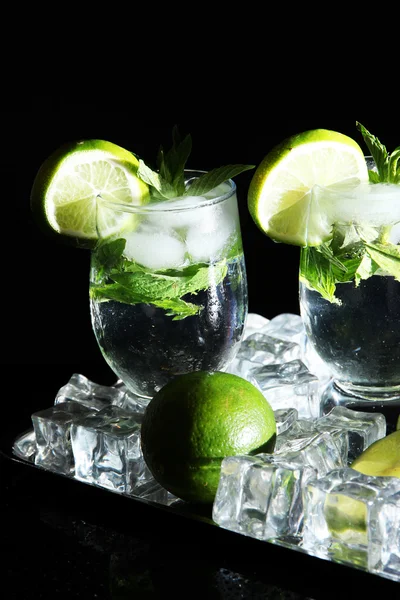 Cocktailgläser mit Eis auf Metalltablett auf schwarzem Hintergrund — Stockfoto