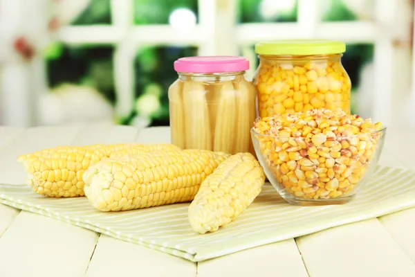 Fresh, canned and dried corn on wooden table, on bright background — Stock Photo, Image