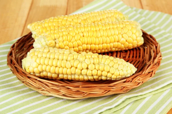 Fresh corn on wicker mat, on wooden background — Stock Photo, Image