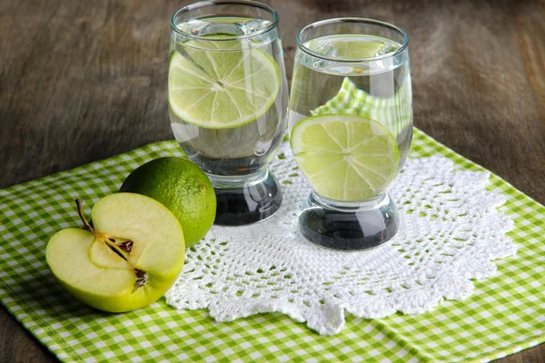 Glasses of cocktail with lime on napkin on dark wooden table — Stock Photo, Image