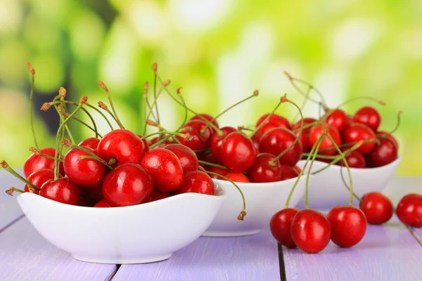 Kirschbeeren in Schale auf Holztisch auf hellem Hintergrund — Stockfoto