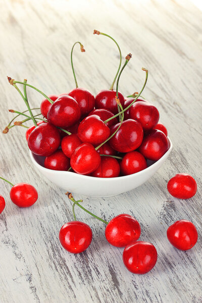 Cherry berries in bowl on wooden table close up