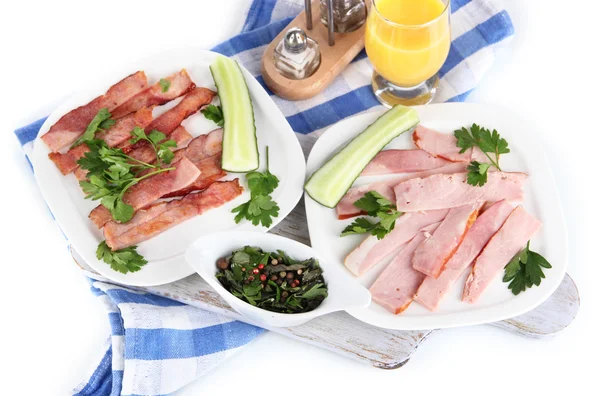 Bacon on plates on napkin on board isolated on white — Stock Photo, Image