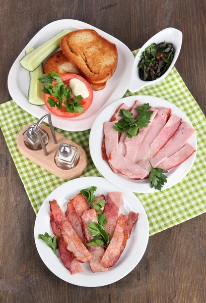 Bacon på tallrikar på servett på träbord — Stockfoto