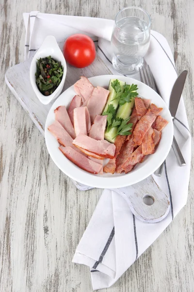 Bacon on plate on board on napkin on board on window table — Stock Photo, Image