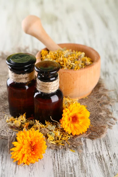 Medicine bottles and calendula flowers on wooden background — Stock Photo, Image