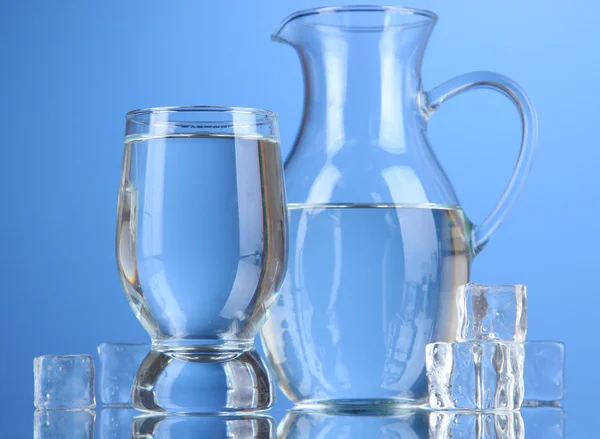 Brocca di vetro di acqua e vetro su sfondo blu — Foto Stock