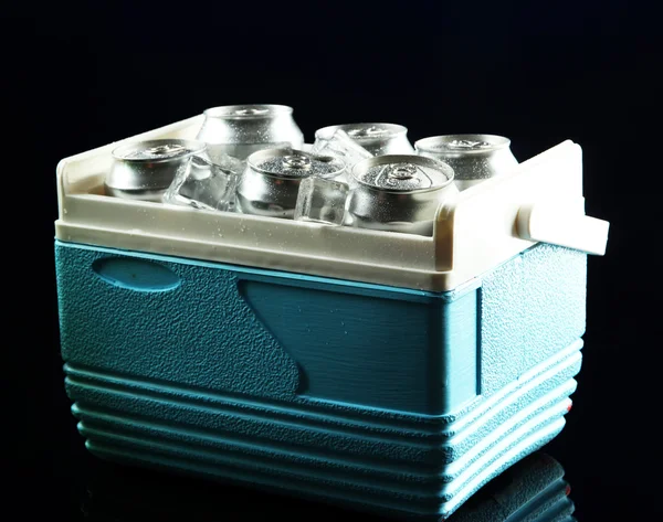 Latas de metal de cerveza con cubitos de hielo en mini refrigerador, sobre fondo azul oscuro — Foto de Stock