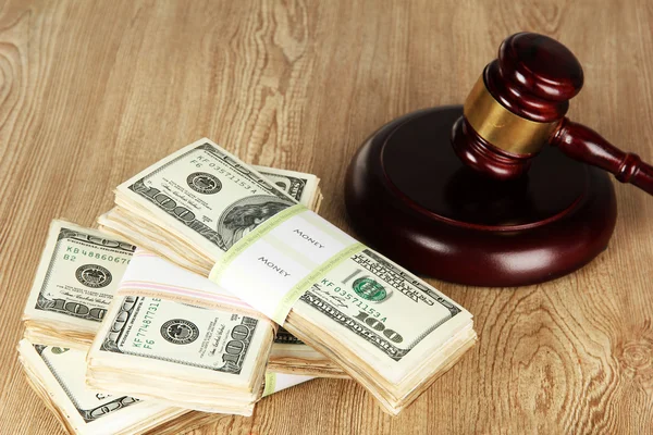 Stacks of money and judges gavel on wooden table — Stock Photo, Image