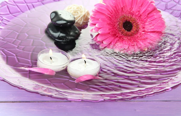 Wellness-Steine, schöne Gerbera und Kerzen auf Wasser — Stockfoto